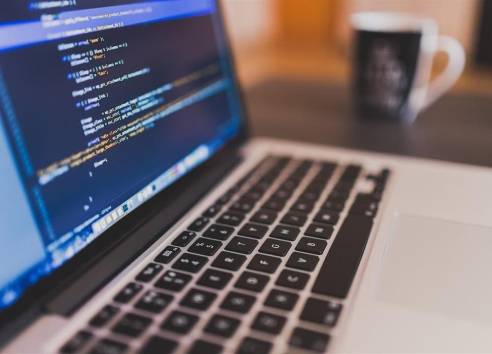 Source code on a laptop screen next to a smartphone