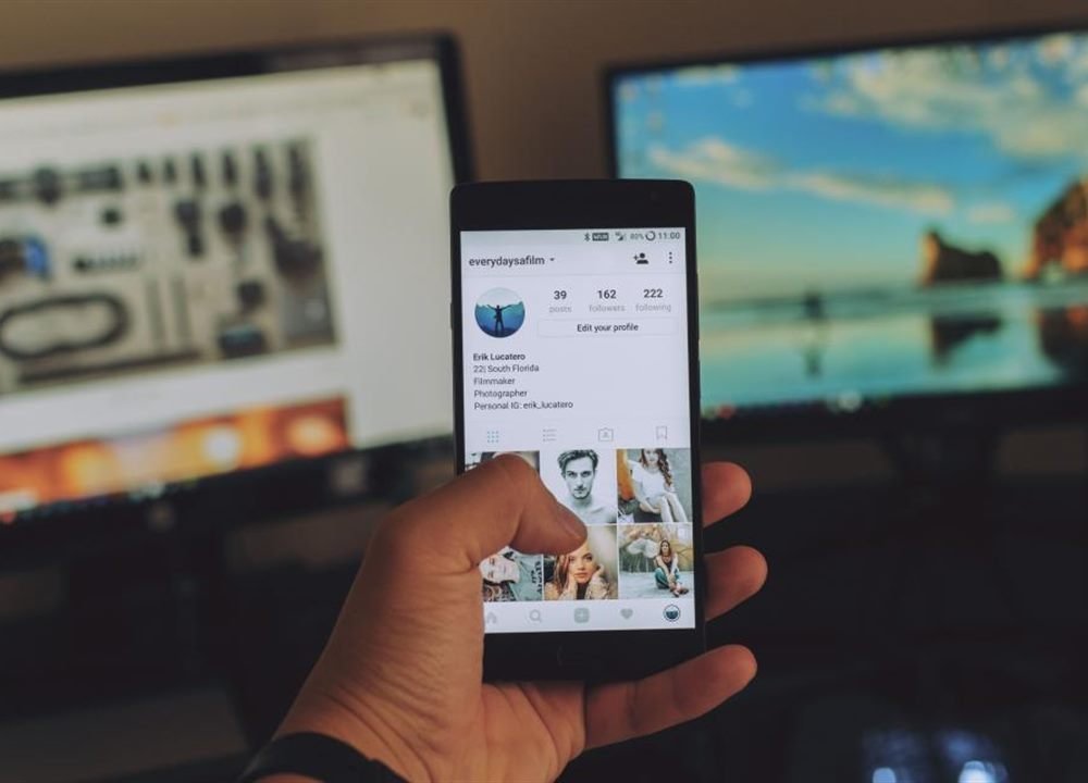 Hand holding a smartphone showing a social media profile