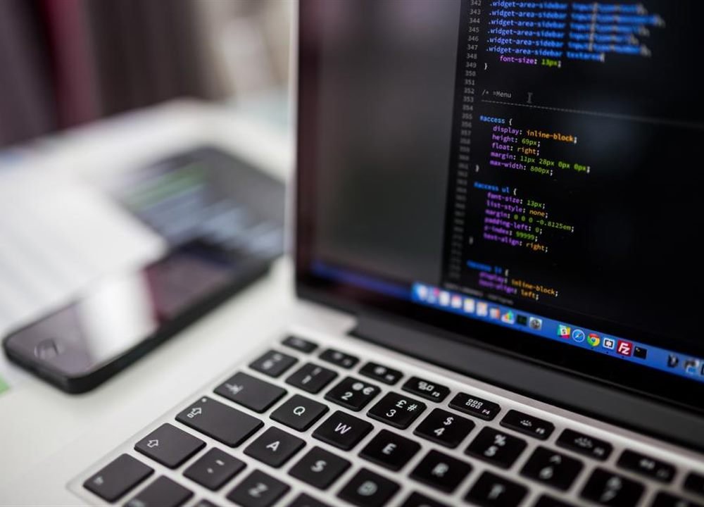 Developer writing code on a laptop for a business website