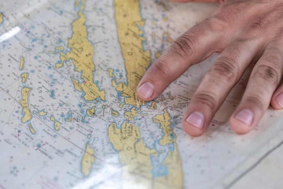 A hand pointing at a location on a paper map