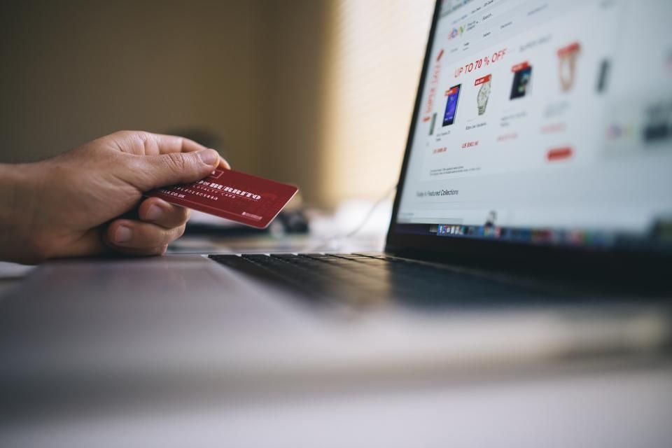 A person paying online with a card on a laptop