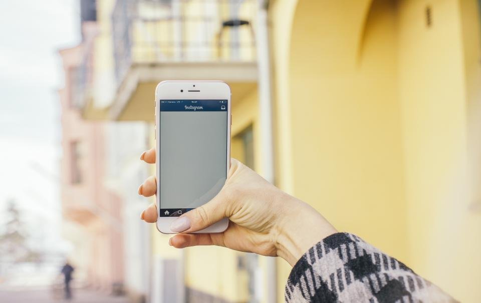 Hand holding a smartphone showing a social media app