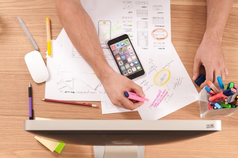 A designer sketching a website wireframe next to a phone and keyboard