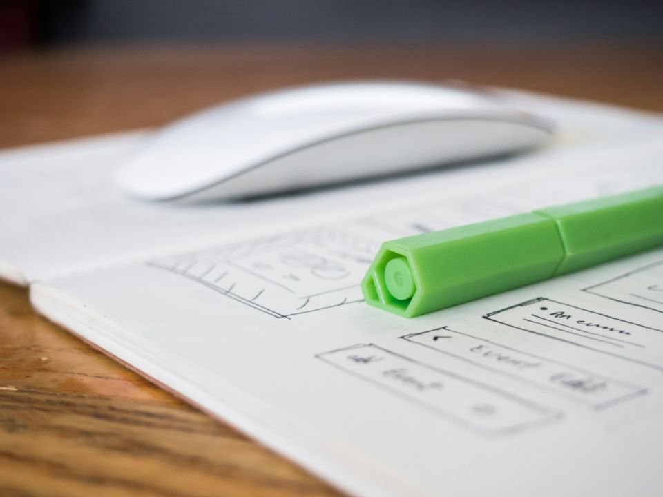 A computer mouse resting on printed website wireframe sketches