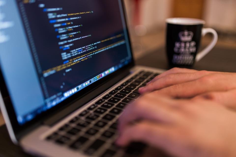 Hands typing code on a laptop for a web development project